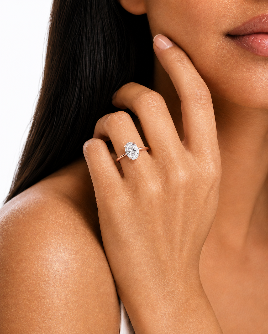 color_10K_RG, color_14K_RG &&A close-up lifestyle shot of a woman wearing a diamond engagement ring on her finger, with her hand resting near her face against a clean white background.