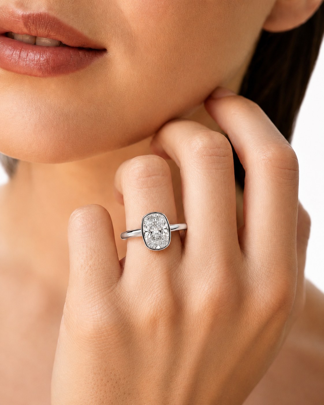 color_925_SIL,color_935_ARG,color_10K_WG, color_14K_WG &&A close-up lifestyle shot of a model wearing a silver oval ring with a clear central gemstone on her finger.