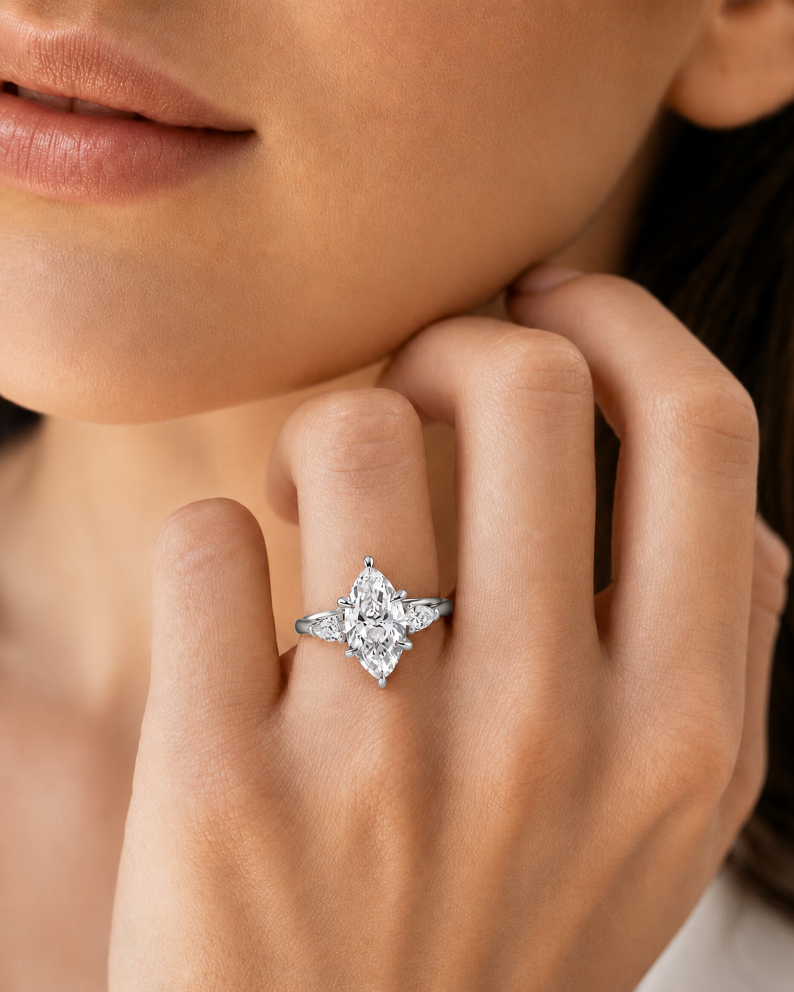 color_925_SIL,color_935_ARG,color_10K_WG, color_14K_WG &&A close-up of a model's hand wearing a silver ring with a marquise-cut center stone and smaller accent stones, set against the model's face and hand.