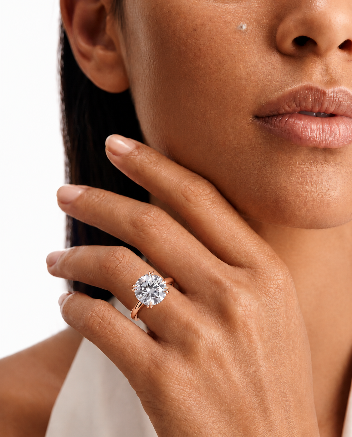 color_10K_RG, color_14K_RG &&A close-up lifestyle shot of a model wearing a rose gold ring with a round-cut clear gemstone on her finger, set against a clean white background.