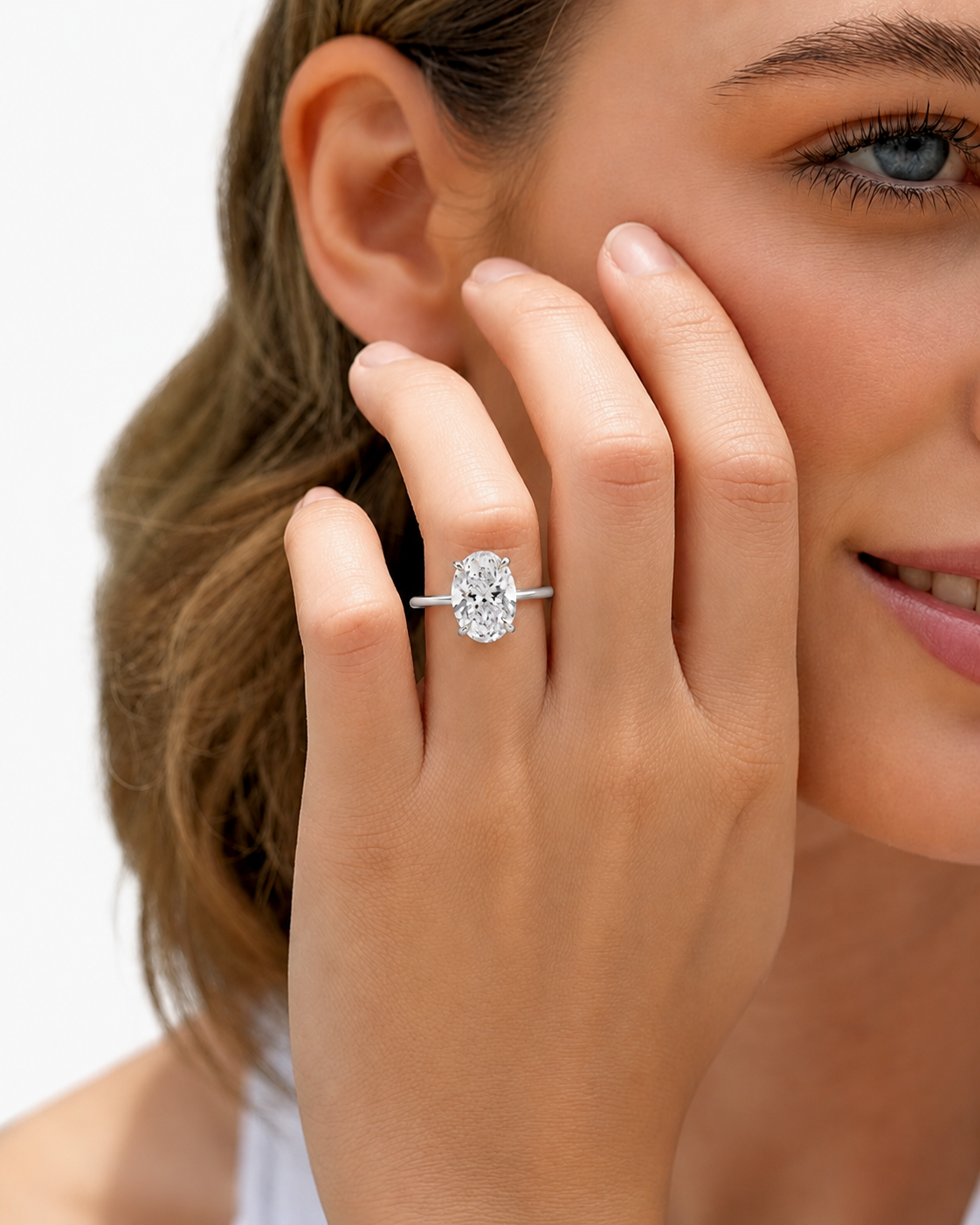 color_925_SIL,color_935_ARG,color_10K_WG, color_14K_WG &&A close-up lifestyle shot of a woman wearing a silver engagement ring with a round-cut clear gemstone on her finger.