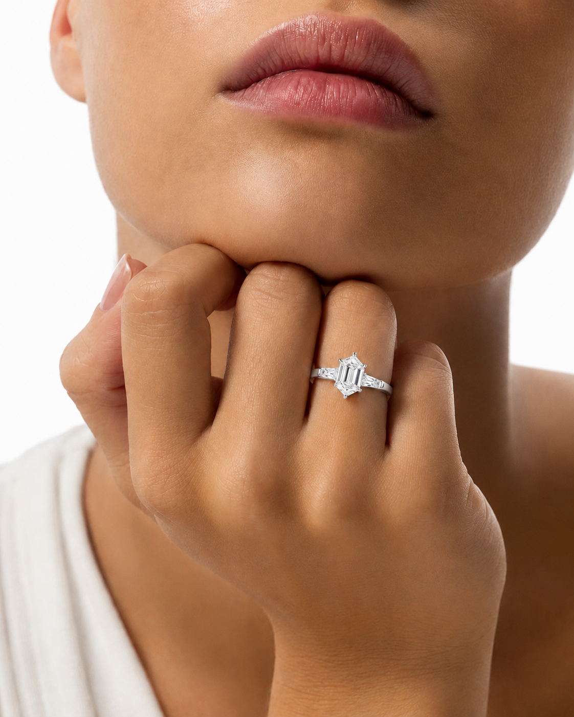 color_925_SIL,color_935_ARG,color_10K_WG, color_14K_WG &&A close-up lifestyle shot of a model wearing a silver ring with a central baguette-cut diamond and smaller side diamonds on her finger.