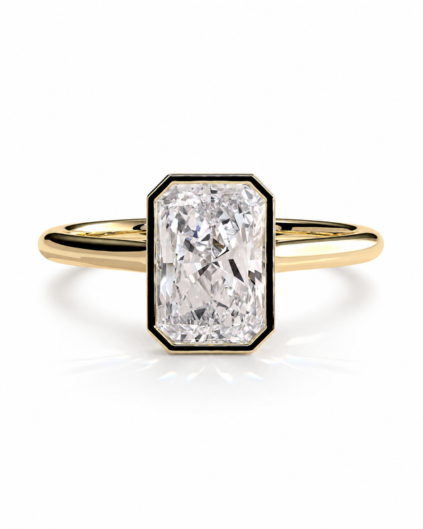 color_10K_YG, color_14K_YG &&A yellow gold ring featuring a large, bezel-set rectangular emerald-cut diamond. The diamond is framed by a black border and sits on a polished yellow gold band, set against a clean white background with a soft reflection.