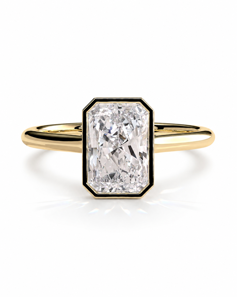 color_10K_YG, color_14K_YG &&A yellow gold ring featuring a large, bezel-set rectangular emerald-cut diamond. The diamond is framed by a black border and sits on a polished yellow gold band, set against a clean white background with a soft reflection.