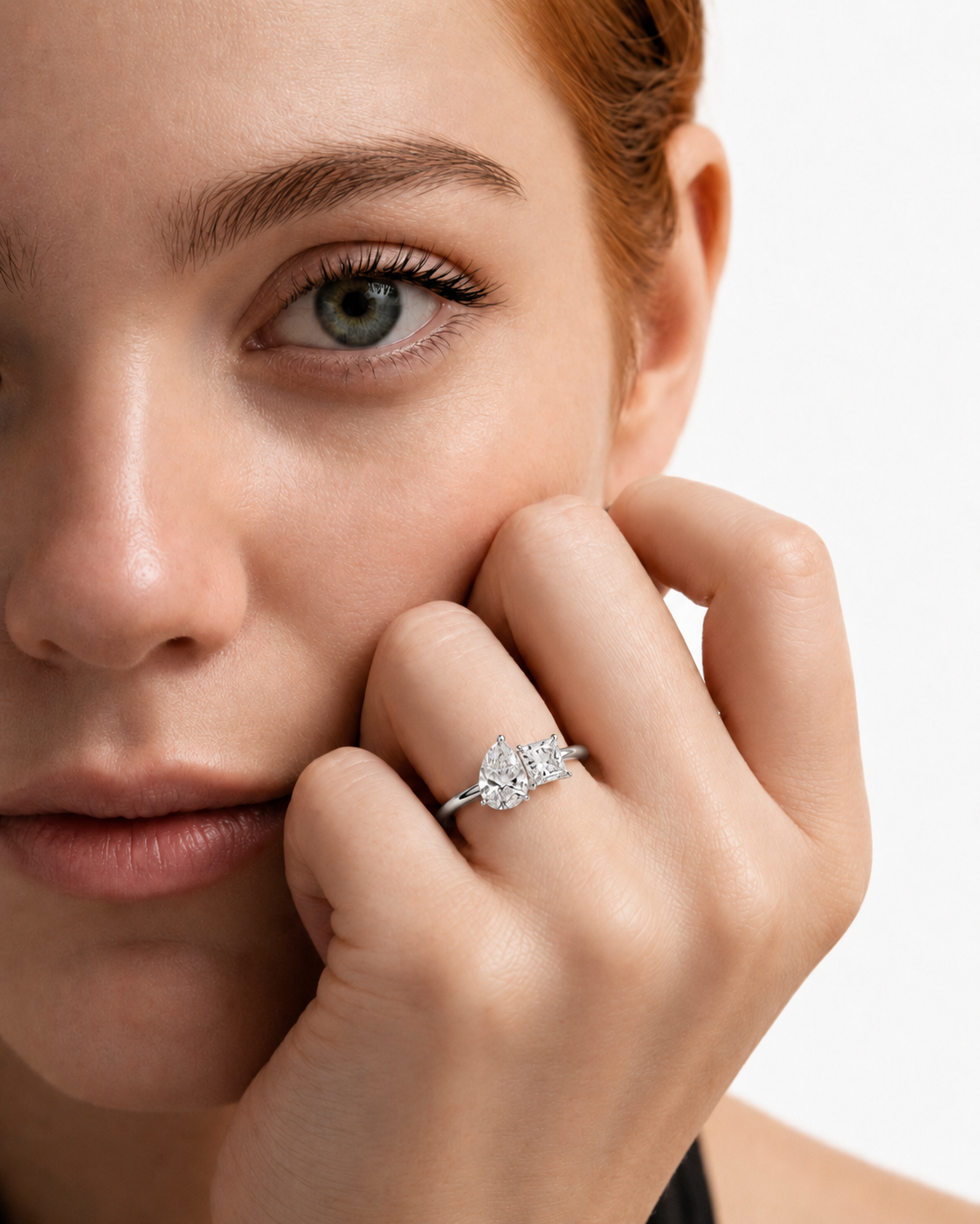 color_925_SIL,color_935_ARG,color_10K_WG, color_14K_WG &&A close-up lifestyle shot of a model with red hair wearing a silver ring with a marquise-cut diamond. The model's face and hand are shown against a clean white background.