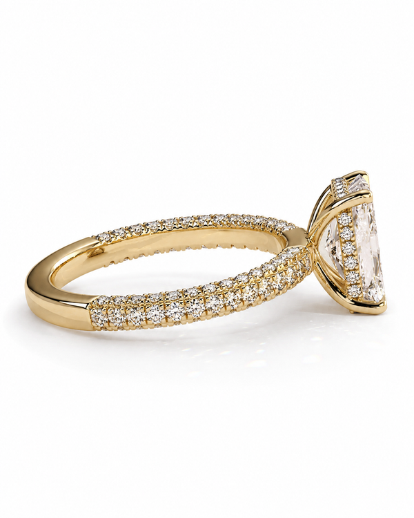color_10K_YG, color_14K_YG &&A yellow gold ring featuring a large cushion-cut clear gemstone in a prong setting, with a pavé band paved with small round diamonds, shown on a white background.