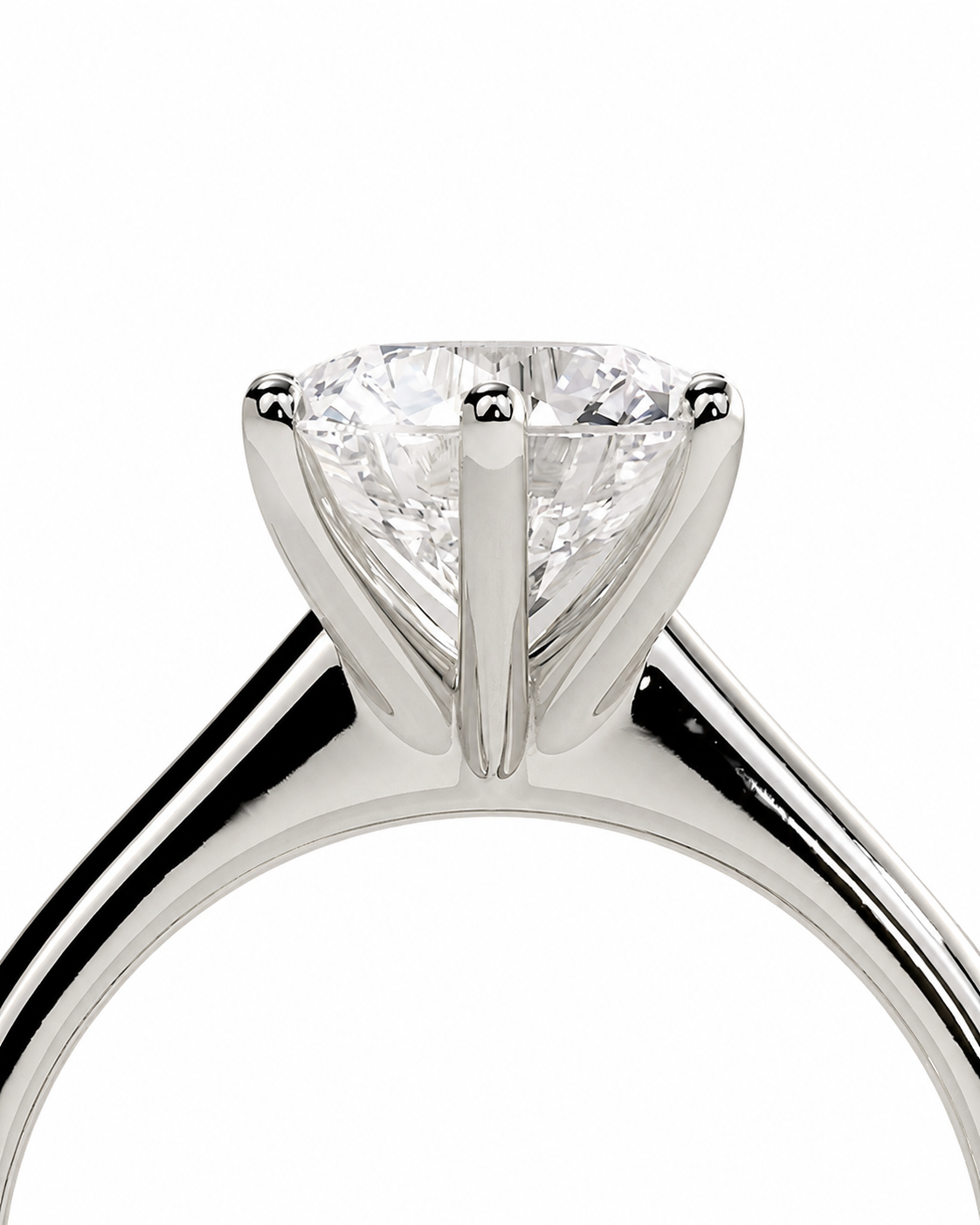 color_925_SIL,color_935_ARG,color_10K_WG, color_14K_WG &&A close-up studio shot of a solitaire engagement ring featuring a brilliant round-cut diamond set in a polished silver-colored metal band, isolated on a white background.