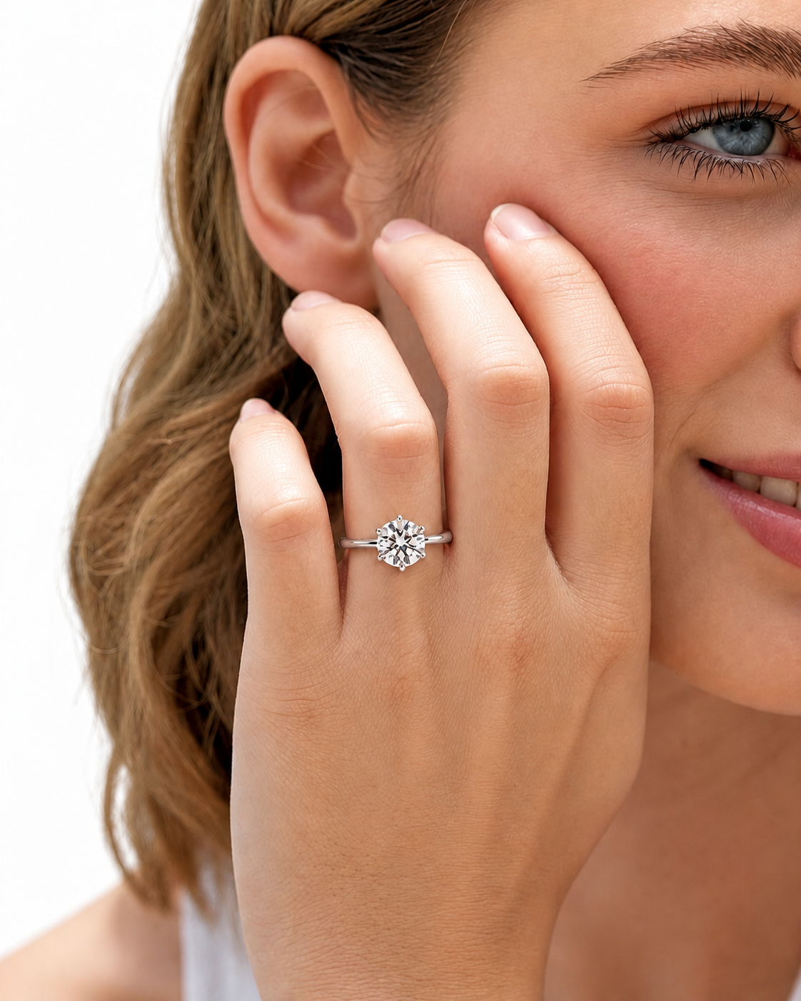 color_925_SIL,color_935_ARG,color_10K_WG, color_14K_WG &&A close-up lifestyle shot of a woman wearing a silver-toned diamond engagement ring on her finger, with her hand resting near her face against a clean white background.