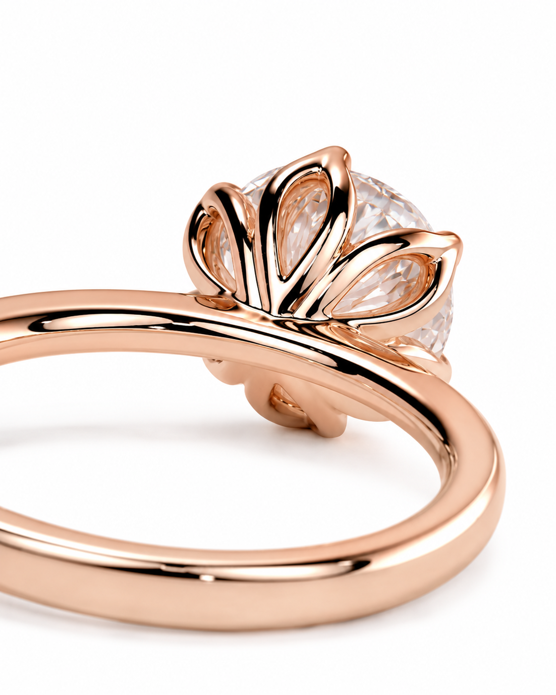 color_10K_RG, color_14K_RG &&A close-up of a rose gold ring featuring a sculptural, leaf-like crown setting holding a clear round gemstone, set against a clean white background.