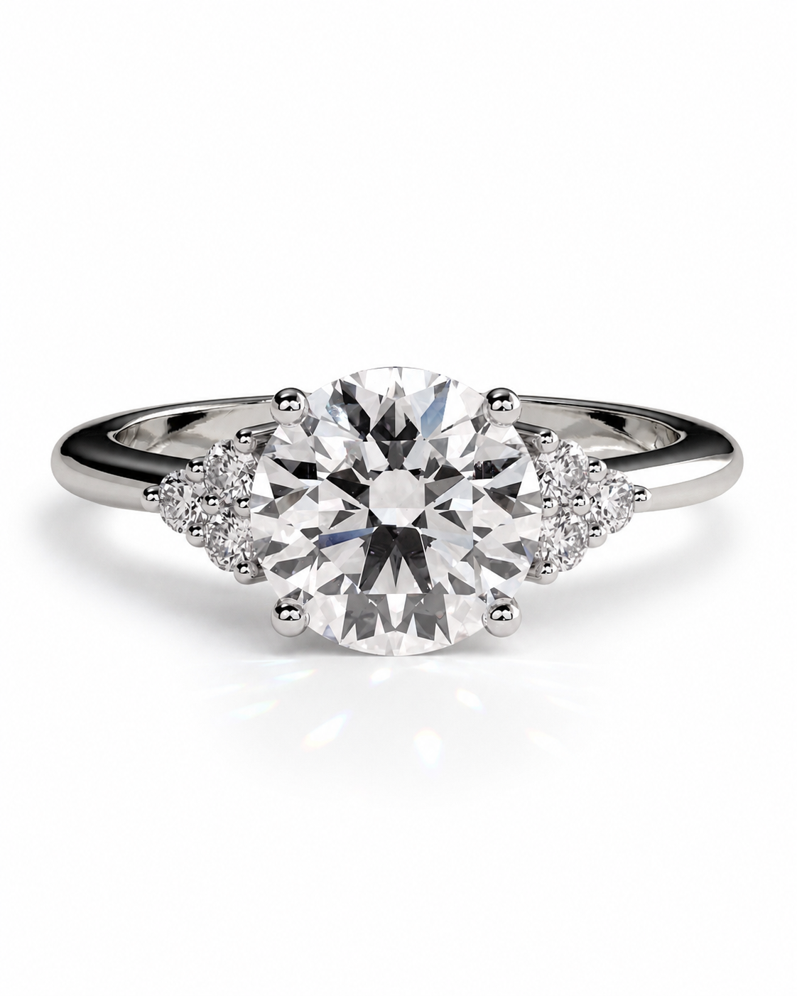 color_925_SIL,color_935_ARG,color_10K_WG, color_14K_WG &&A silver engagement ring featuring a large round-cut center stone with smaller round-cut accent stones on either side of the band, set against a clean white background.