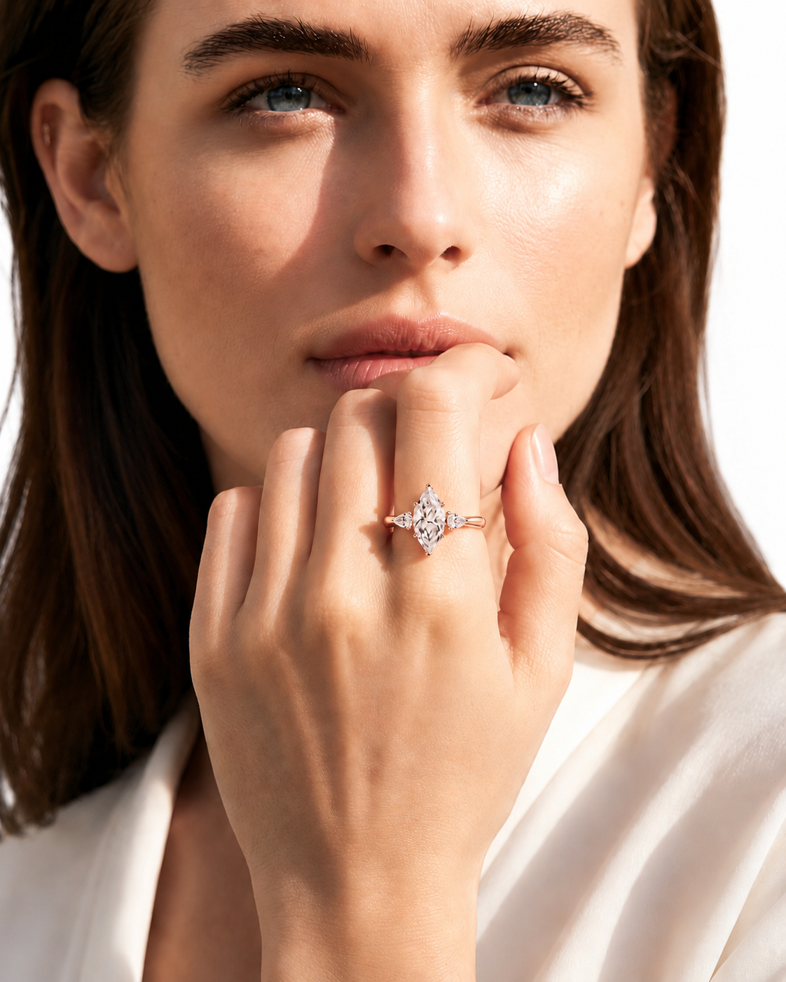 color_10K_RG, color_14K_RG &&A close-up lifestyle shot of a woman wearing a delicate rose gold ring with a starburst diamond setting. The ring is positioned on her index finger, with her hand resting near her chin, set against a clean white background.
