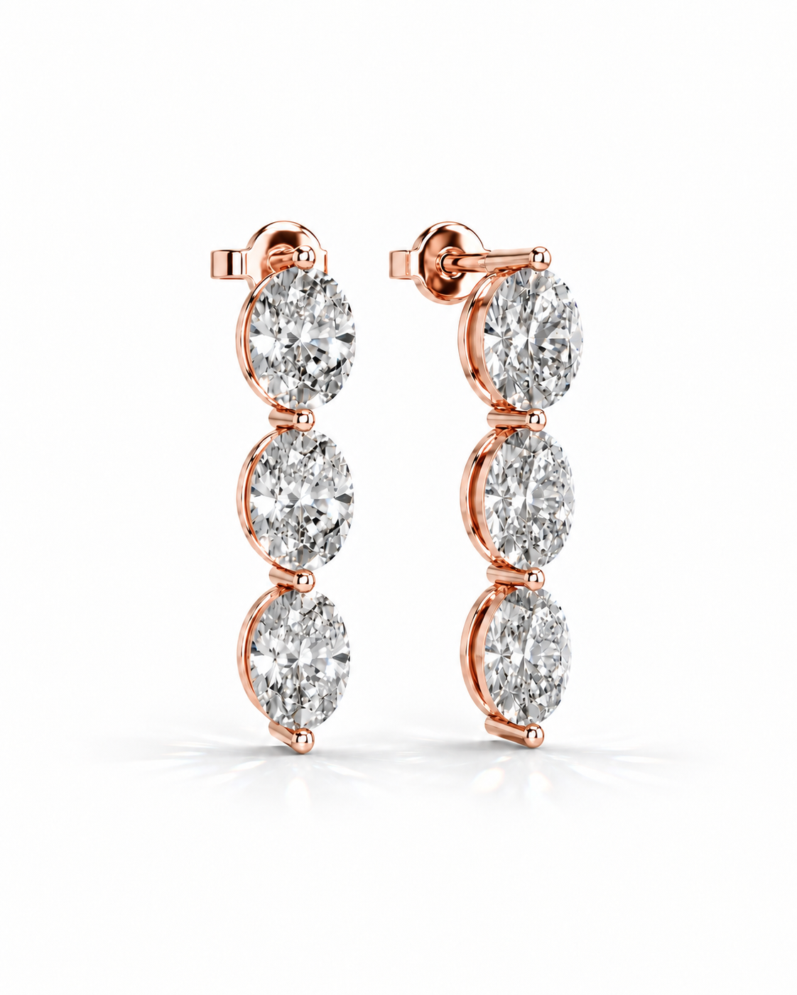 color_10K_RG, color_14K_RG &&A pair of rose gold drop earrings featuring three round-cut clear gemstones in a vertical setting, shown on a clean white background.