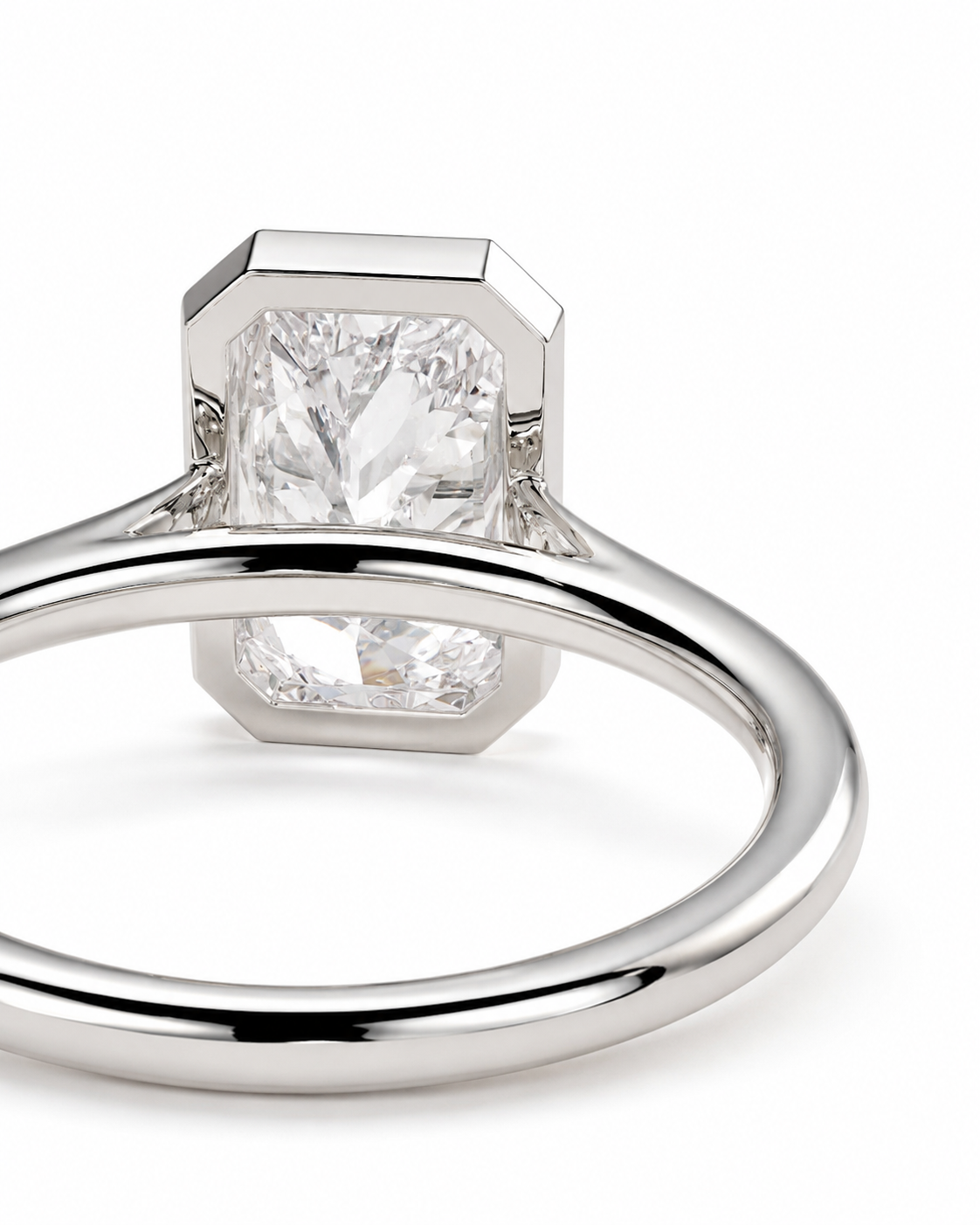 color_925_SIL,color_935_ARG,color_10K_WG, color_14K_WG &&Side profile of a bezel set radiant cut moissanite engagement ringA close-up studio shot of a silver-toned ring featuring a large, clear, emerald-cut diamond. The diamond is held in an octagonal bezel setting on a polished band, photographed against a seamless white background.