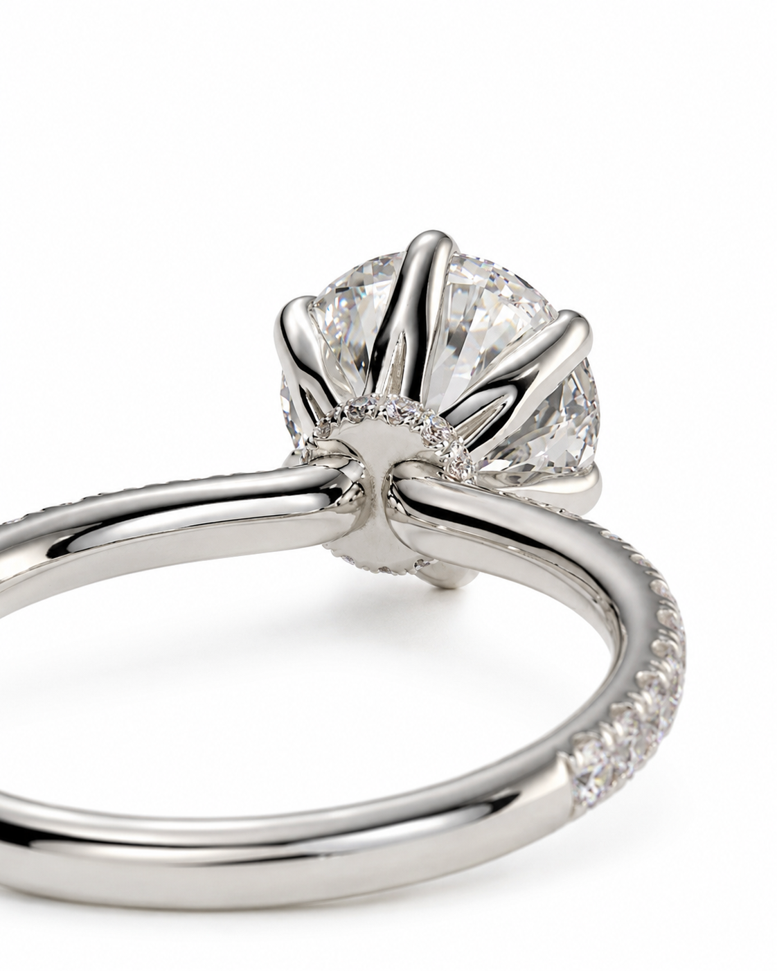 color_925_SIL,color_935_ARG,color_10K_WG, color_14K_WG &&A close-up studio shot of a silver-toned diamond engagement ring, showing the crown prongs, a round brilliant-cut center diamond, and a pavé-set band on a white background.