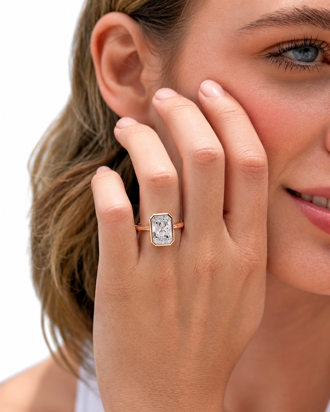 color_10K_RG, color_14K_RG &&A close-up lifestyle shot of a woman wearing a rose gold ring with a rectangular clear gemstone on her finger, set against a clean white background.